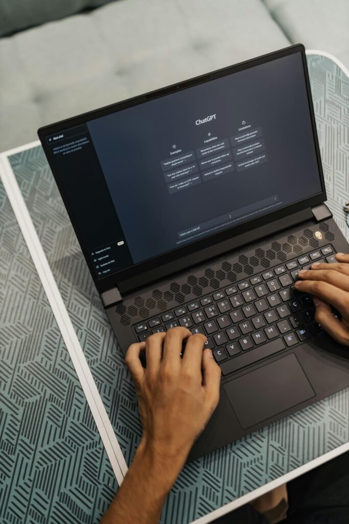 Person typing on a high-performance gaming laptop with sleek design, showcasing ChatGPT on the screen